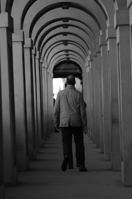 Žmogus eina koridoriumi, o lubinis judesio jutiklis fiksuoja judėjimą ir valdo šviesą.