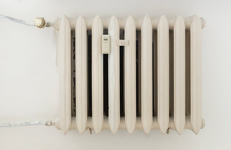 Asmuo reguliuoja išmanų termostatą prie radiatoriaus, matyti šildymo kontrolė